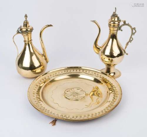 Two Middle Eastern brass coffee pots and a circular brass pl...