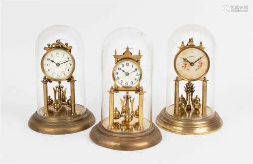 Three German 400 day anniversary clocks in glass and perspex...