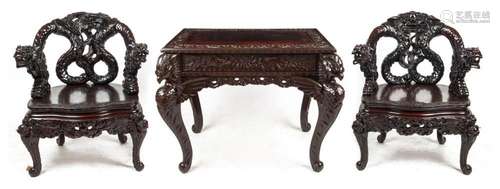 An antique Chinese table and two armchairs with carved drago...