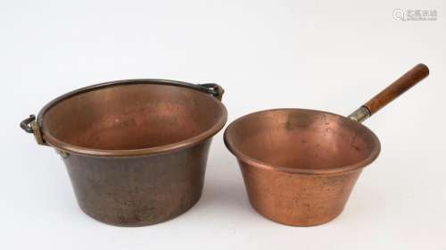 A copper preserving pan and a copper saucepan with a wooden ...