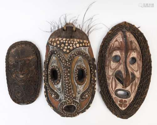 Three tribal masks, carved wood, shell, cane and feather wit...
