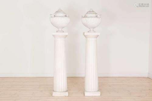 A pair of plaster urns on pedestals,