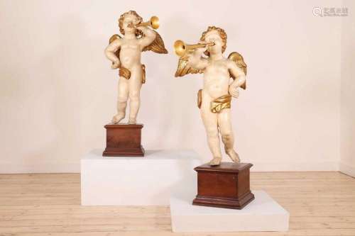 A pair of painted and parcel-gilt wooden putti,