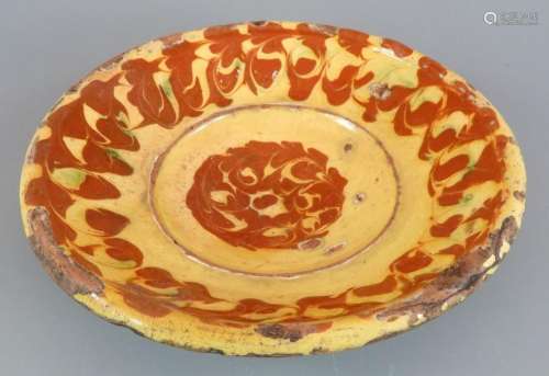 An early nineteenth century slipware dish, c. 1800. It is de...
