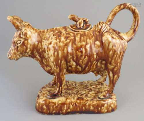 A mid-nineteenth century treacle glaze cow creamer and lid, ...