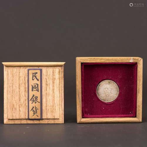 A SILVER COIN WITH JAPANESE BOX