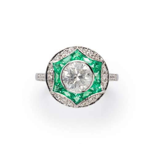 A diamond, emerald and eighteen karat white gold ring