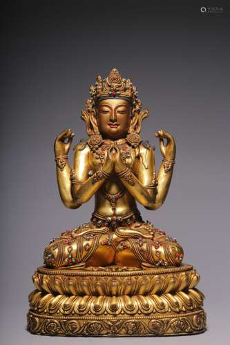 A sitting statue of Guanyin with four arms and bronze gilt i...