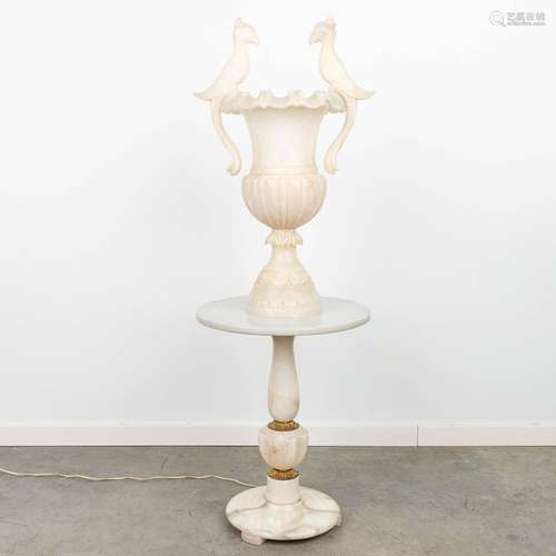 A lamp decorated with birds on a marble stand and made of al...