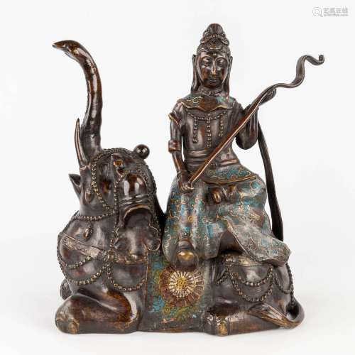 A figurine of Guanyin seated on an elephant, patinated bronz...