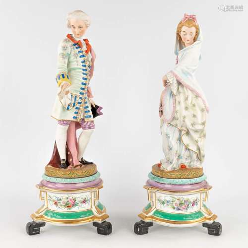 A pair of antique bisque figurines, standing on a glazed por...