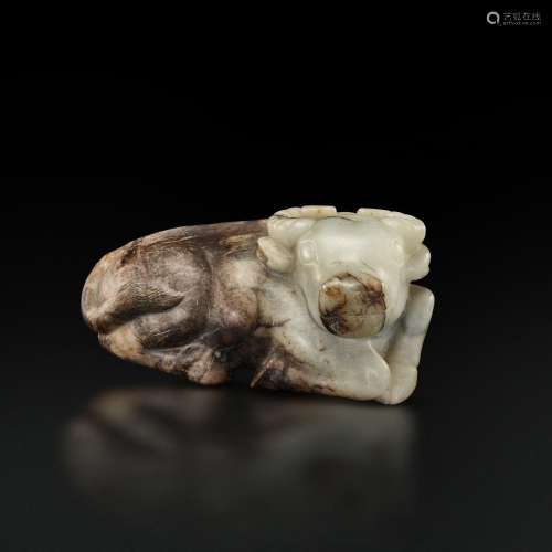 A large white and brown jade figure of a recumbent buffalo, ...