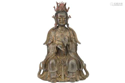 A Chinese bronze figure of Guanyin, seated wearing long robe...