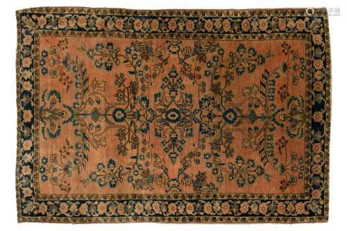 An old Sarouk rug with floral sprays on a typical dusky pink...