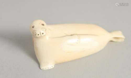 AN INUIT CARVED BONE MODEL OF A SEAL. 3ins long.
