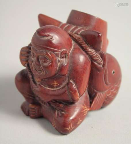 A CARVED WOOD FISHERMAN WITH A CARP. Signed, 2ins.
