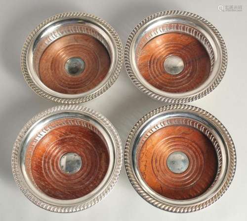 A SET OF FOUR SILVER PLATED CIRCULAR WINE COASTERS with turn...