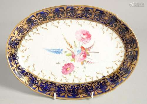 A GOOD OVAL DISH with blue and gilt border and painted with ...