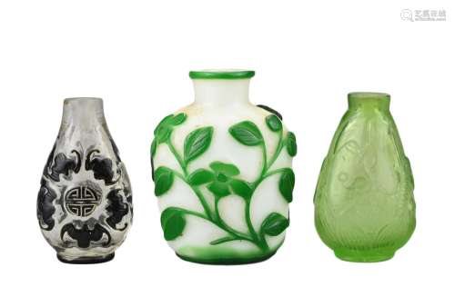 THREE CHINESE GLASS SNUFF BOTTLES. Comprising a green-overla...