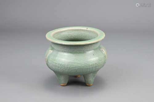 A CHINESE CELADON GLAZED TRIPOD CENSER. Compressed body with...