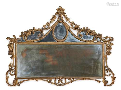 A CARVED GILTWOOD AND COMPOSITION OVER MANTLE WALL MIRROR IN...