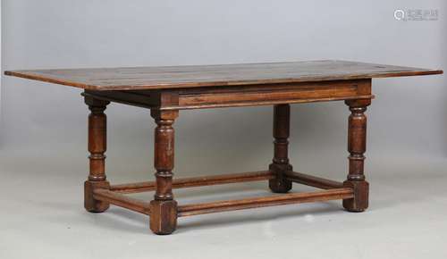 A 17th century style oak refectory table, raised on turned a...