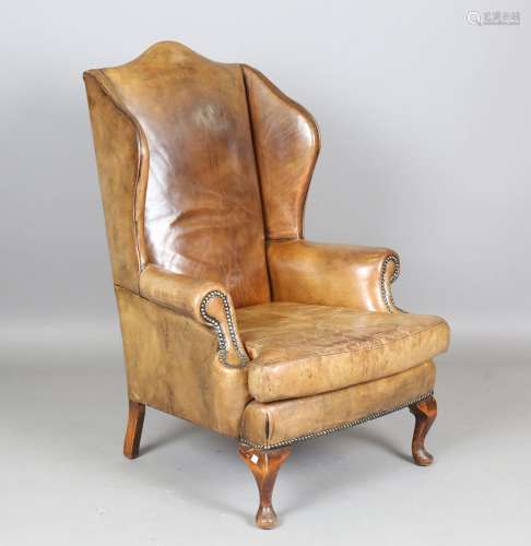 A mid-20th century George III style green leather wingback a...
