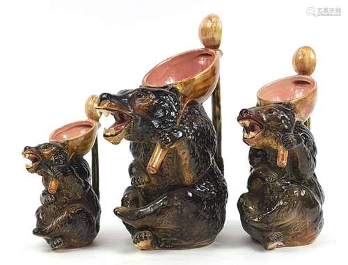 Graduated set of three Majolica style brown bear jugs, the l...