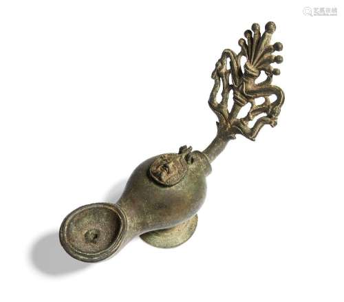 A Roman-style bronze oil lamp with elaborate open work handl...