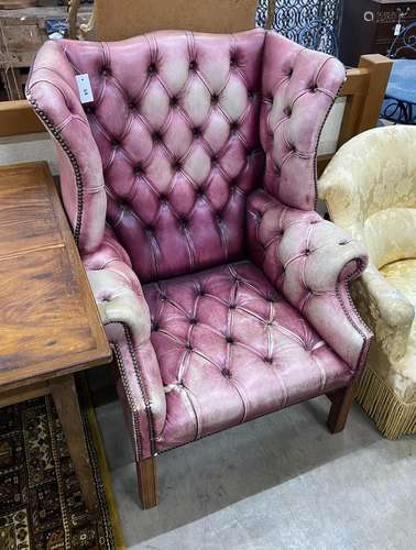 A George III style button back wing armchair upholstered in ...