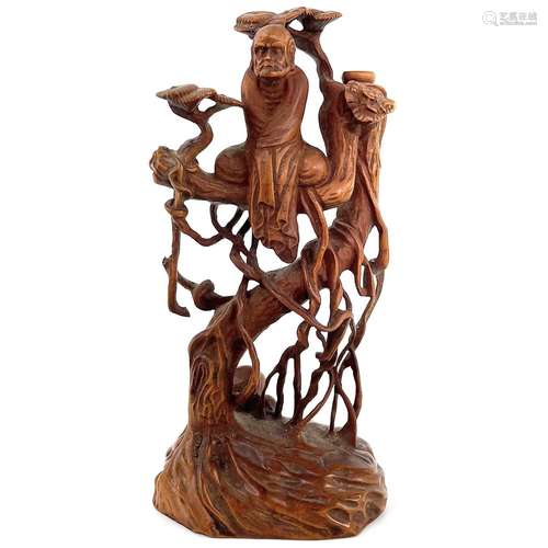 A Chinese carved boxwood figure of a man seated in a tree, e...