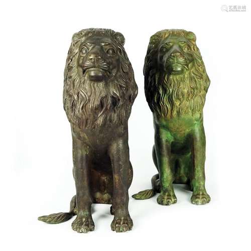 A pair of patinated bronze sitting lions