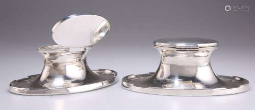 A NEAR PAIR OF GEORGE V SILVER OVAL CAPSTAN INKWELLS