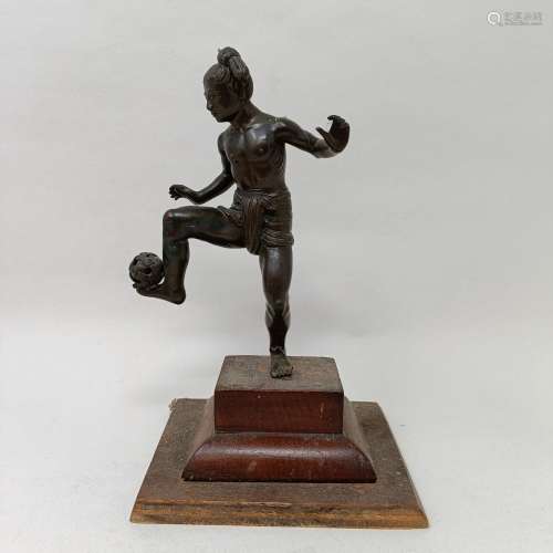 A bronze figure of a man playing Sepek Takraw, on a wooden b...