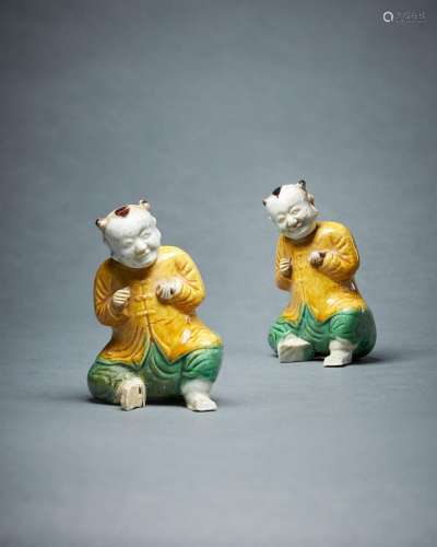A pair of Chinese biscuit glazed models of seated smiling bo...