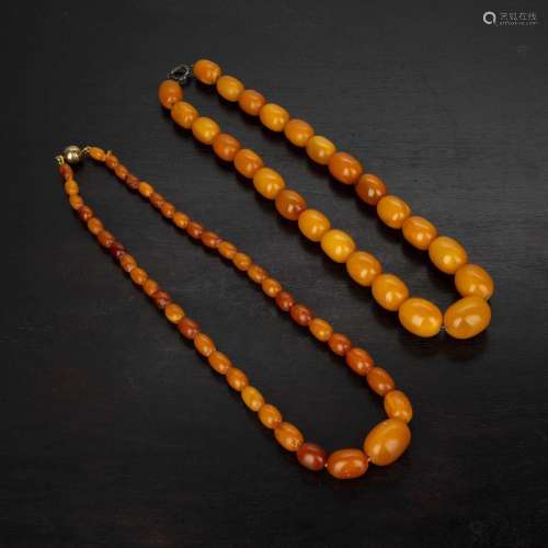 Two amber bead necklaces both of graduated form, the larger ...