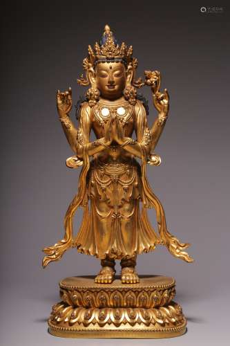 A statue of Guanyin with four arms inlaid with gold and bron...