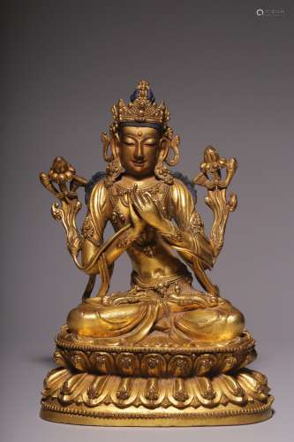A sitting statue of Guanyin with four arms and bronze gilt i...