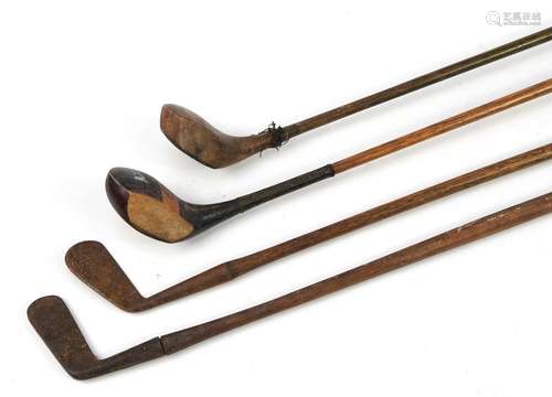 Four early 20th century wooden shafted golf clubs, the large...