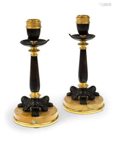A pair of French gilt and patinated bronze candlesticks, lat...