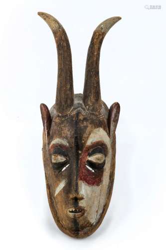 An African carved wooden mask, polychrome painted, with horn...
