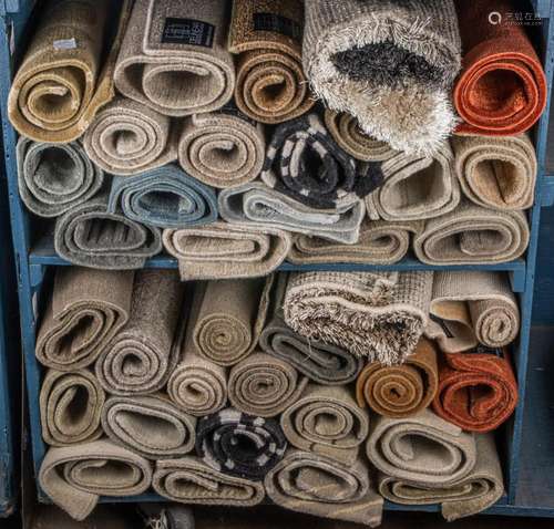 Two shelves of small hand knotted rugs, some by Chris Baisan...