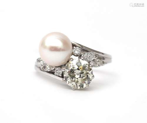 A 14 karat white gold diamond and pearl cross over ring. Fea...