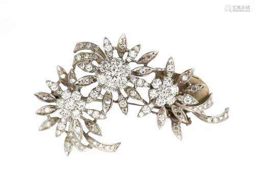 A 14 karat white gold diamond flower brooch. Featuring singl...