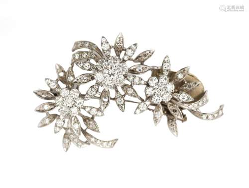 A 14 karat white gold diamond flower brooch. Featuring singl...