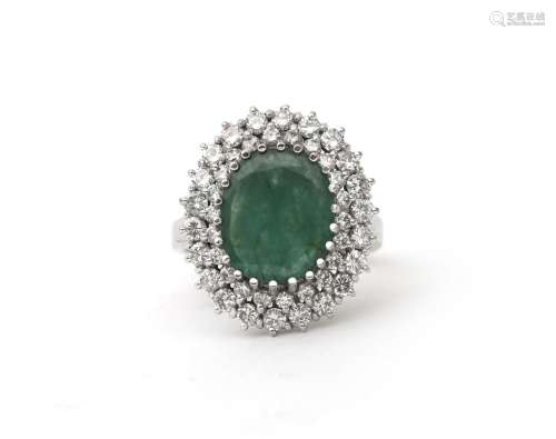 A 14 karat white gold emerald and diamond cluster ring. Feat...