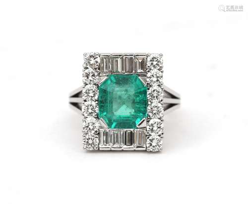 An 18 karat white gold emerald and diamond cluster ring. Fea...