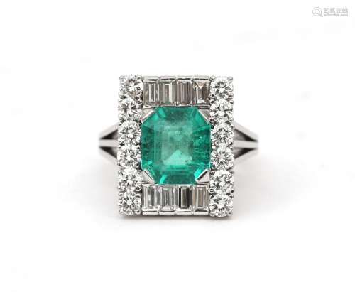 An 18 karat white gold emerald and diamond cluster ring. Fea...