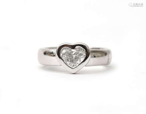 A 14 karat white gold ring with a heart cut diamond. Central...