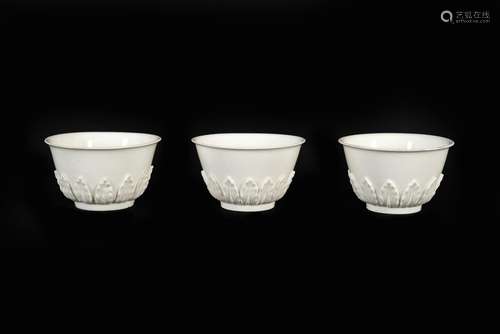 A set of three white glazed porcelain cups with relief decor...